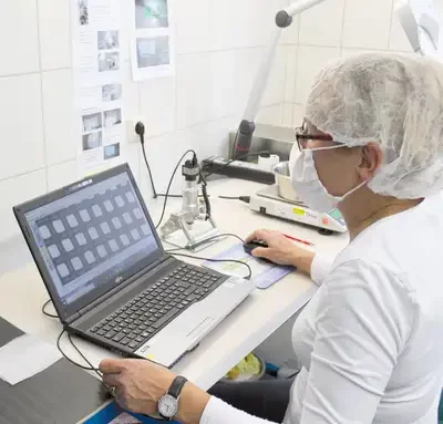 Mitarbeiterin bei der mikroskopischen Qualitätskontrolle von industriellen Filterbeuteln im Labor
