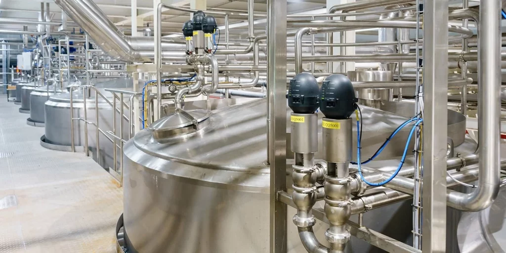 Edelstahl-Filteranlage in der Produktion der Lebensmittel- und Pharmaindustrie mit großen Kesseln und Rohrleitungen.
