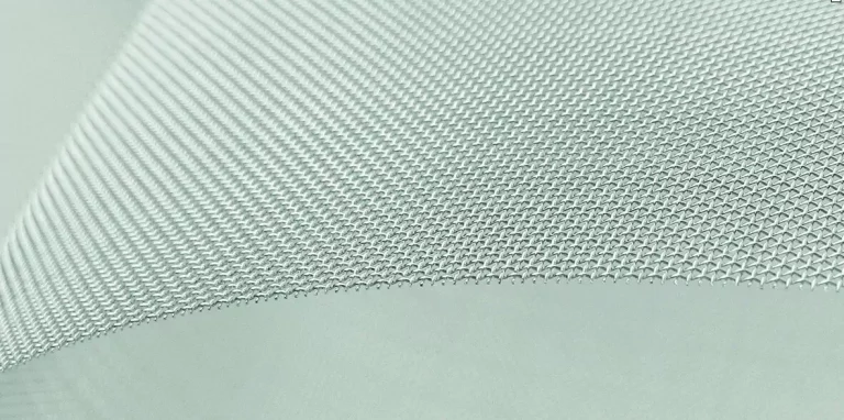 Nahaufnahme eines grauen Industriefilters aus feinem Metallgewebe mit erkennbarer Webstruktur.